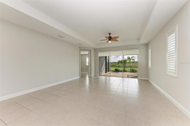 tiled spare room featuring ceiling fan and a raised ceiling