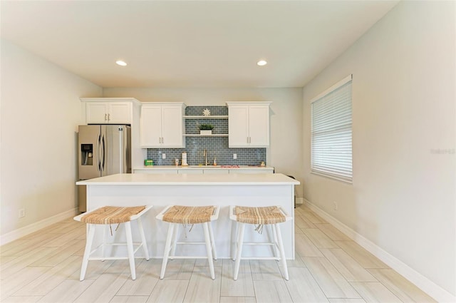 kitchen with white cabinetry, a kitchen breakfast bar, and stainless steel refrigerator with ice dispenser