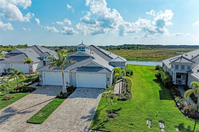 view of front of property with a garage, a front lawn, and a water view