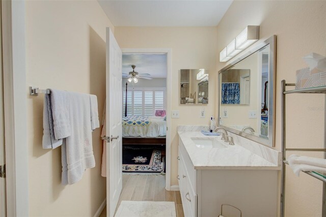 bathroom with wood-type flooring, ceiling fan, and vanity with extensive cabinet space