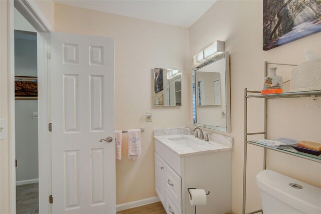 bathroom with vanity with extensive cabinet space, toilet, and hardwood / wood-style floors