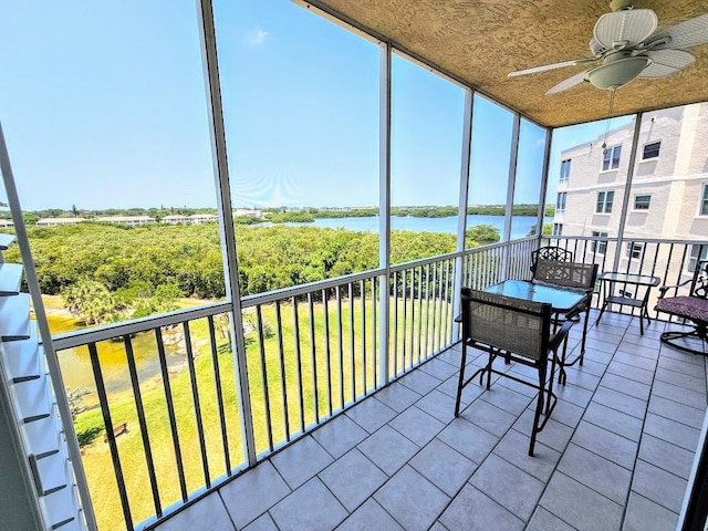 sunroom / solarium featuring a water view and ceiling fan