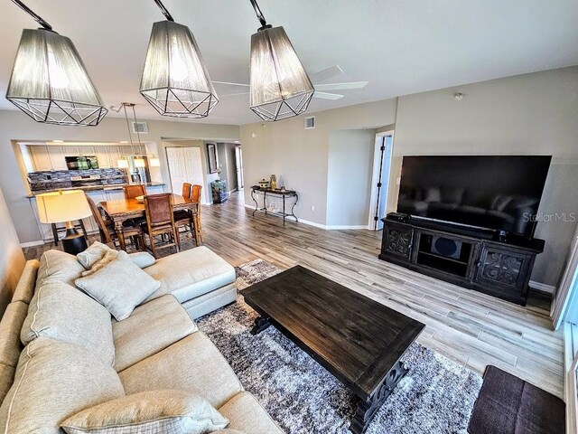 living room with light wood-type flooring and ceiling fan