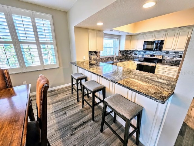 kitchen with a breakfast bar, kitchen peninsula, backsplash, and stainless steel range with electric cooktop