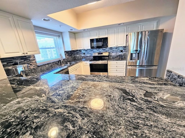 kitchen with appliances with stainless steel finishes, sink, backsplash, and dark stone counters