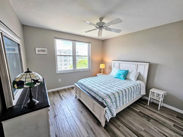 bedroom featuring a textured ceiling, dark hardwood / wood-style floors, and ceiling fan