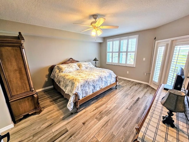 bedroom featuring ceiling fan, light hardwood / wood-style floors, a textured ceiling, and multiple windows