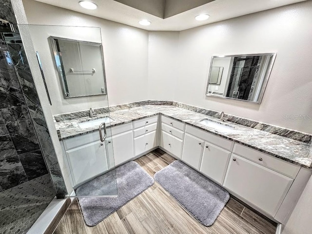 bathroom with a tile shower, vanity, and hardwood / wood-style flooring