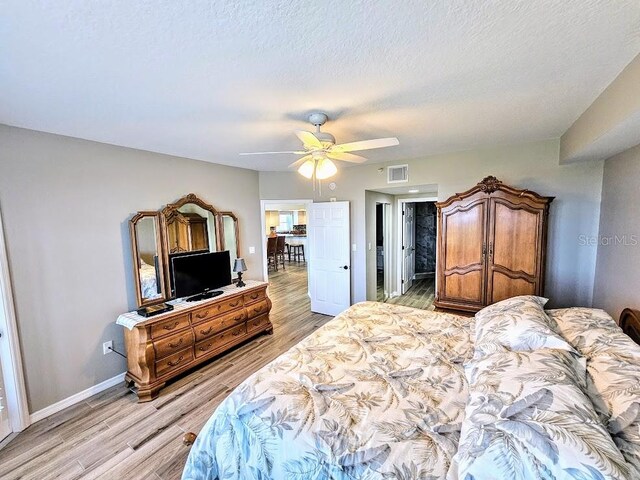 bedroom featuring a textured ceiling, ceiling fan, and light wood-type flooring