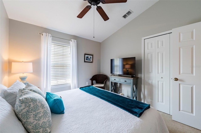 carpeted bedroom with ceiling fan, a closet, and vaulted ceiling