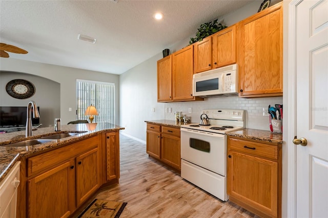 kitchen featuring sink, dark stone countertops, and white appliances