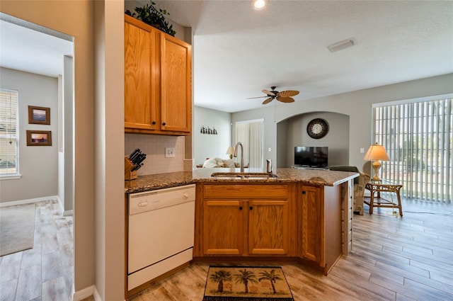 kitchen with ceiling fan, dishwasher, stone counters, decorative backsplash, and sink