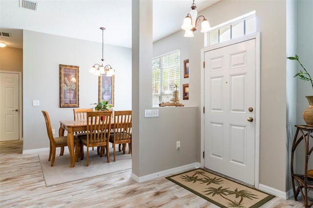 foyer entrance with light hardwood / wood-style floors and a chandelier