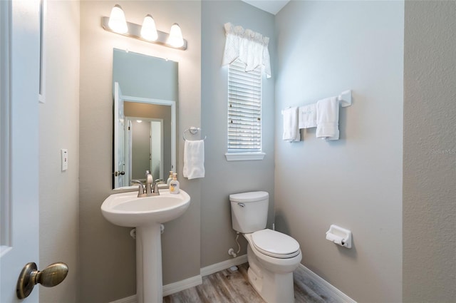 bathroom featuring toilet, a healthy amount of sunlight, and hardwood / wood-style flooring