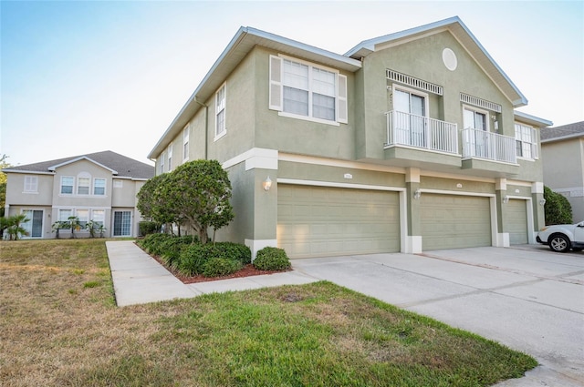 townhome / multi-family property featuring a front lawn, a garage, and a balcony