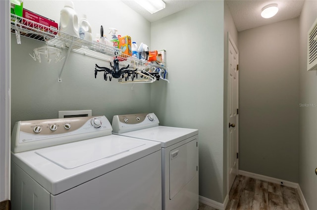 washroom featuring hardwood / wood-style flooring, a textured ceiling, and washing machine and clothes dryer