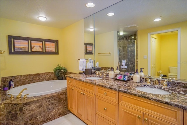 bathroom with tile floors, a relaxing tiled bath, toilet, and double sink vanity