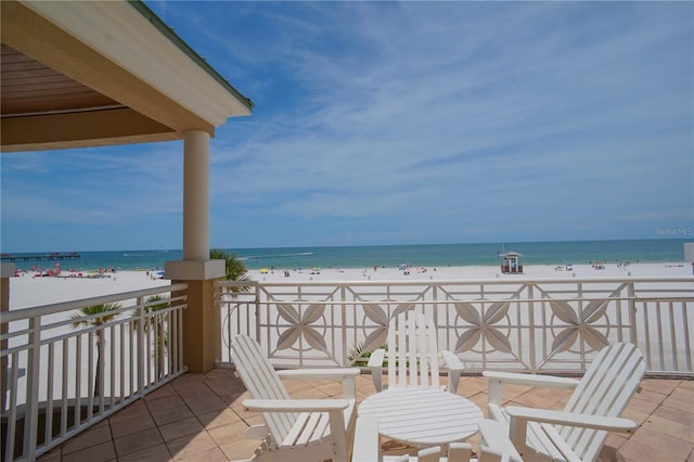 view of patio / terrace featuring a view of the beach, a balcony, and a water view