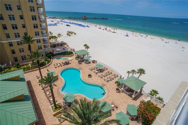 view of swimming pool with a beach view, a water view, and a patio