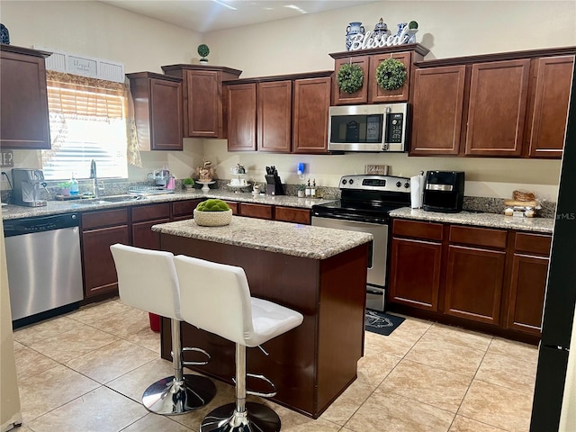 kitchen featuring stainless steel appliances, sink, a center island, and light tile patterned floors