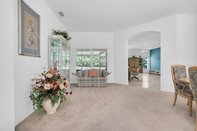 living area with ceiling fan, a healthy amount of sunlight, and light carpet