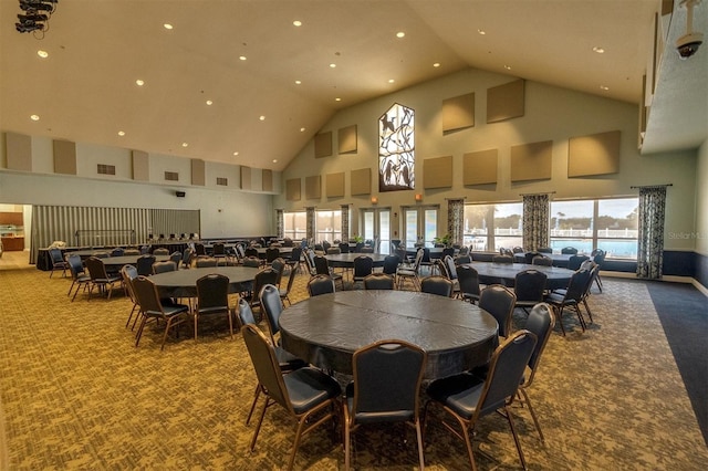 dining room featuring a water view, a towering ceiling, and carpet floors