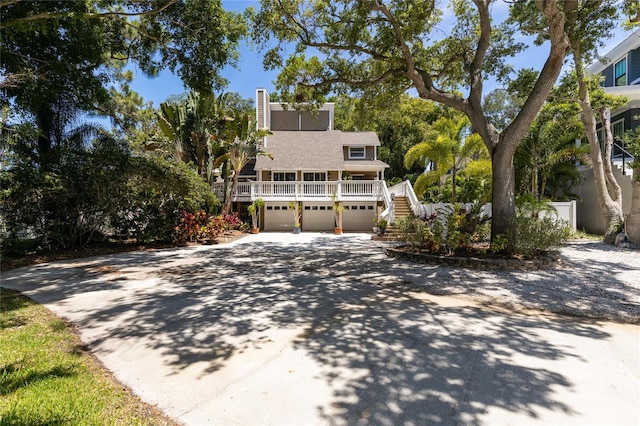 view of front of house with driveway, a garage, stairway, and a porch