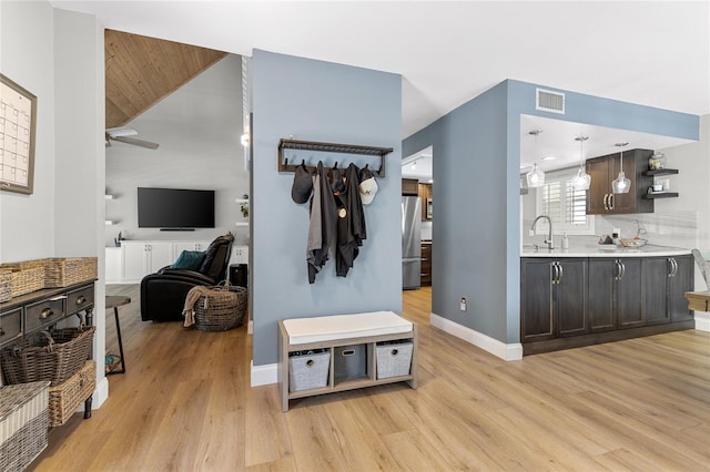 interior space featuring light wood finished floors, visible vents, a ceiling fan, a sink, and baseboards