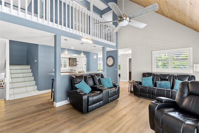 living area featuring light wood finished floors, ceiling fan, stairway, and baseboards