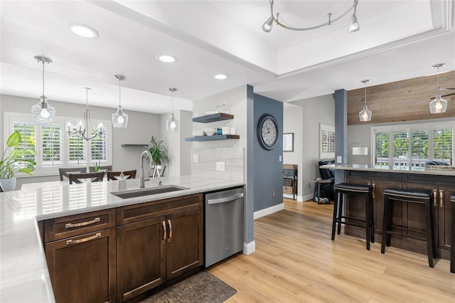 kitchen featuring stainless steel dishwasher, a sink, and pendant lighting