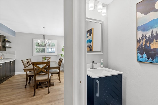 dining space with light wood finished floors, baseboards, and an inviting chandelier