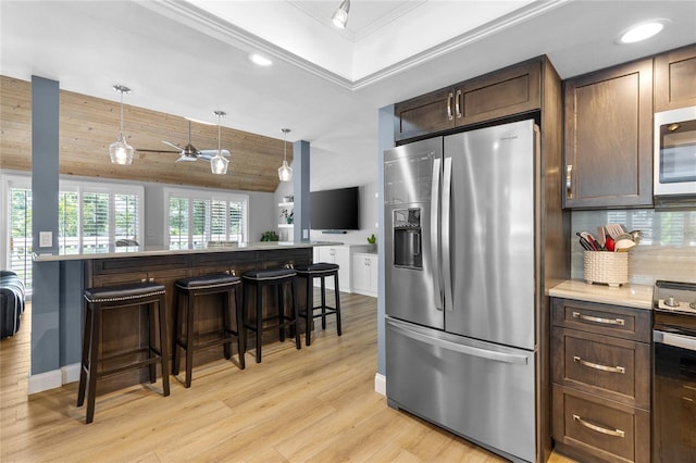 kitchen with stainless steel appliances, a breakfast bar area, light countertops, and decorative light fixtures