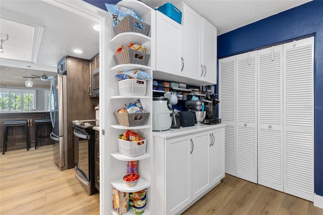 kitchen featuring stainless steel appliances, light countertops, white cabinets, and light wood-style floors