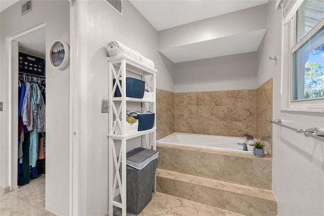 bathroom featuring visible vents, a spacious closet, and a bath