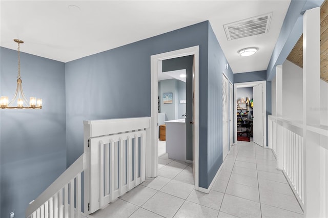 corridor featuring light tile patterned floors, an upstairs landing, visible vents, and an inviting chandelier