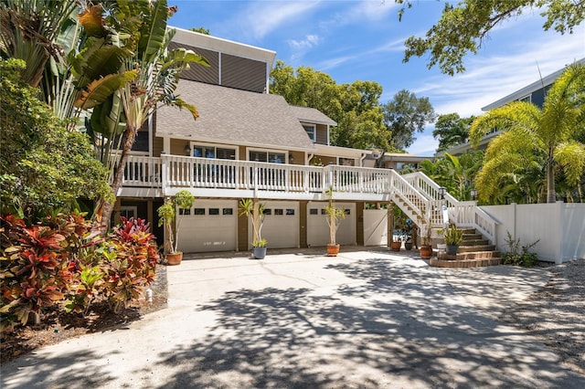 back of property featuring a porch, a garage, fence, driveway, and stairway