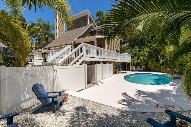 outdoor pool with stairway, fence, a deck, and a patio