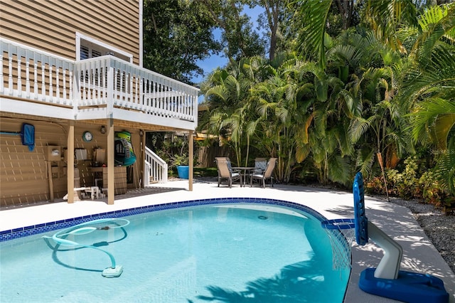 outdoor pool with stairs, fence, and a patio