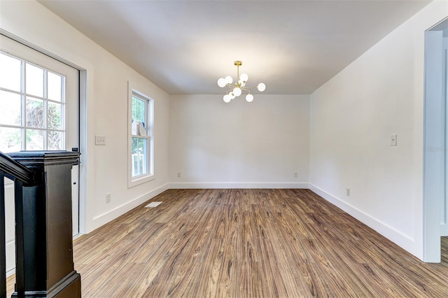 spare room with hardwood / wood-style flooring and an inviting chandelier