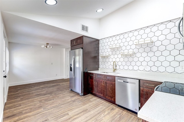 kitchen with appliances with stainless steel finishes, hardwood / wood-style flooring, sink, tasteful backsplash, and vaulted ceiling