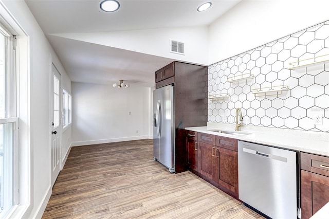 kitchen with backsplash, hardwood / wood-style flooring, appliances with stainless steel finishes, sink, and lofted ceiling