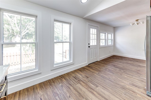 entryway with a healthy amount of sunlight, hardwood / wood-style floors, and vaulted ceiling