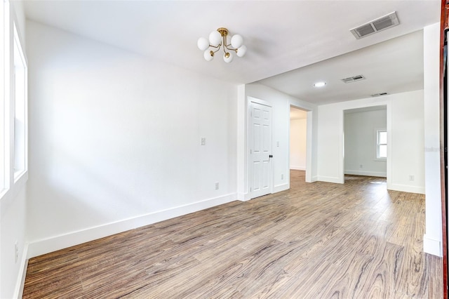 spare room featuring a notable chandelier and hardwood / wood-style flooring