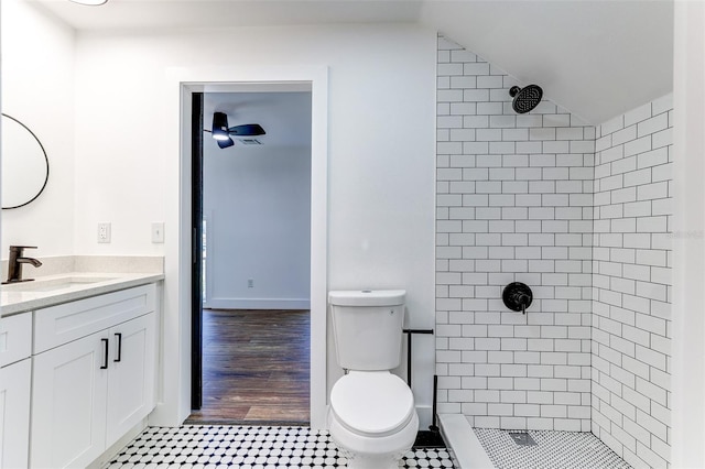 bathroom featuring a tile shower, toilet, wood-type flooring, vanity, and vaulted ceiling