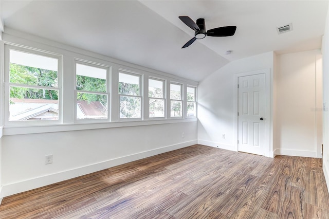 unfurnished room featuring plenty of natural light, wood-type flooring, ceiling fan, and vaulted ceiling