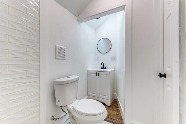 bathroom featuring hardwood / wood-style flooring, vanity, toilet, and vaulted ceiling