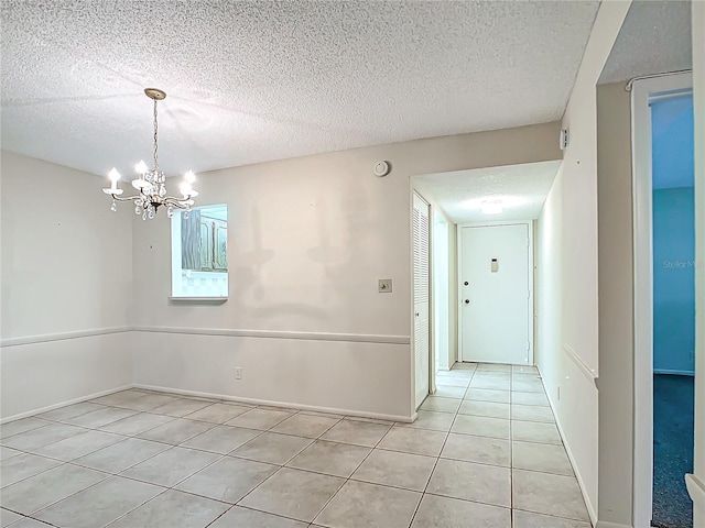 unfurnished dining area featuring a textured ceiling, light tile patterned floors, and an inviting chandelier