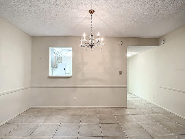 tiled empty room featuring a textured ceiling and a notable chandelier