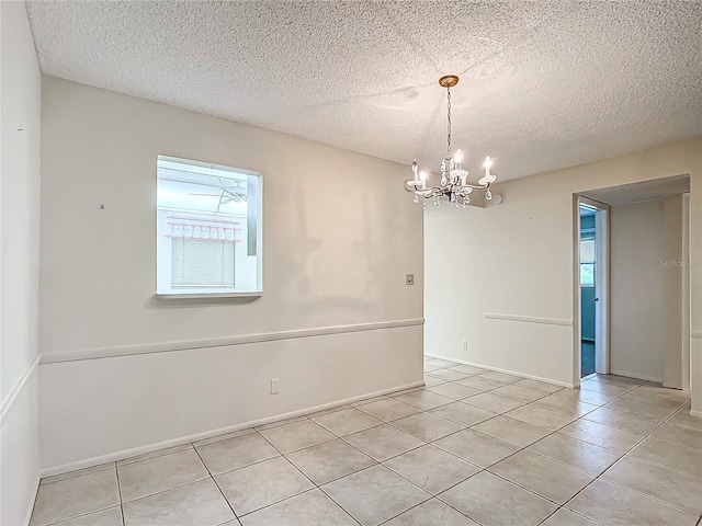 unfurnished room featuring light tile patterned flooring, an inviting chandelier, and a textured ceiling