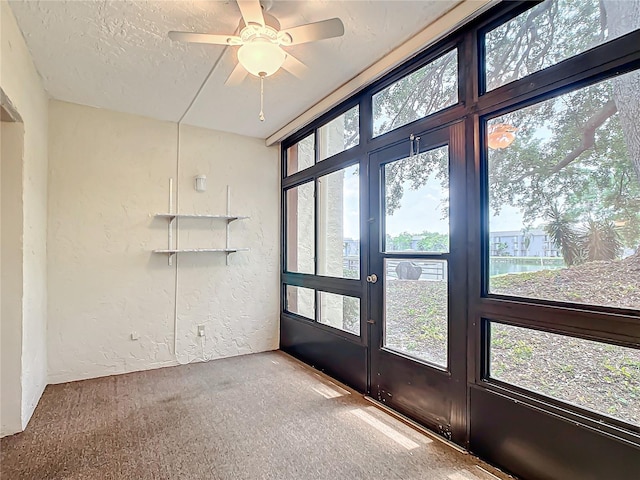 unfurnished sunroom with ceiling fan and a water view